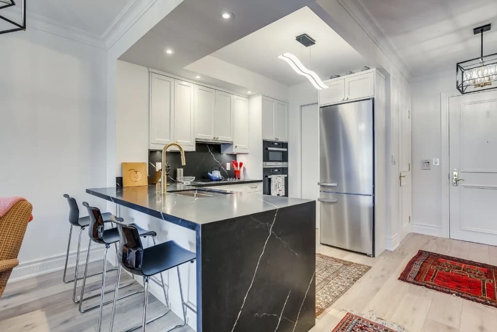 Modern condo kitchen renovation with marble island and white cabinetry in Toronto
